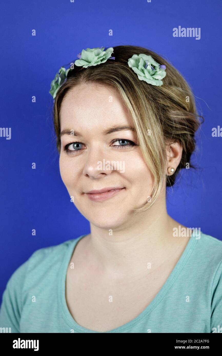 Junge blonde Frau mit Hochbehaarung und Cyan-Blüten Stockfoto