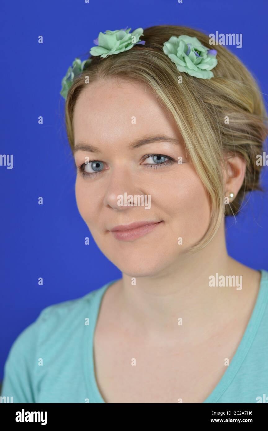 Junge blonde Frau mit Hochbehaarung und Cyan-Blüten Stockfoto