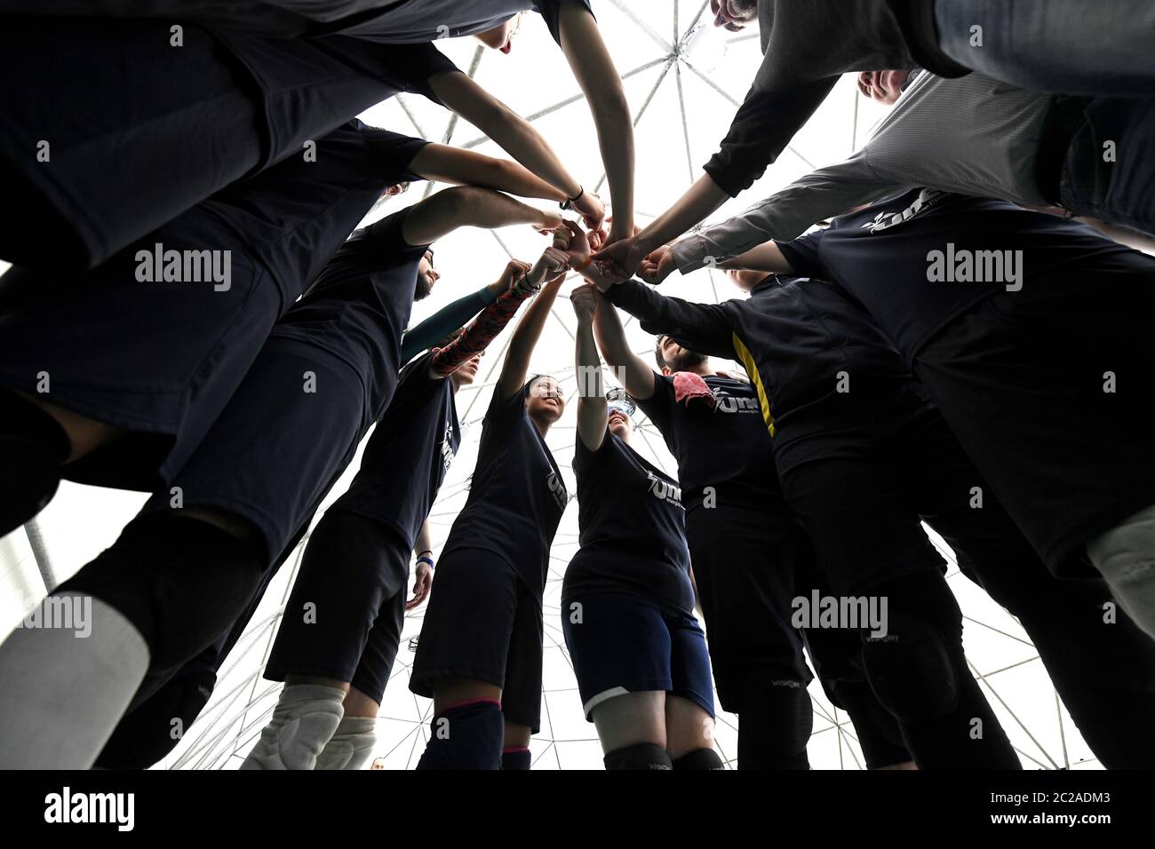 Weibliche und männliche Teamkollegen, die sich gegenseitig unterstützen, indem sie die Hände im Kreis halten, während eines Tchouklball-Spiels in Mailand. Stockfoto
