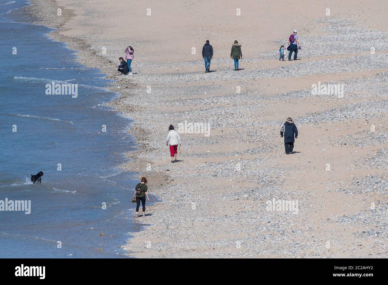Menschen, die am Fistral Beach in Cornwall spazieren und die soziale Distanz aufgrund der Coronavirus Covid 19 Pandemie aufrechterhalten. Stockfoto