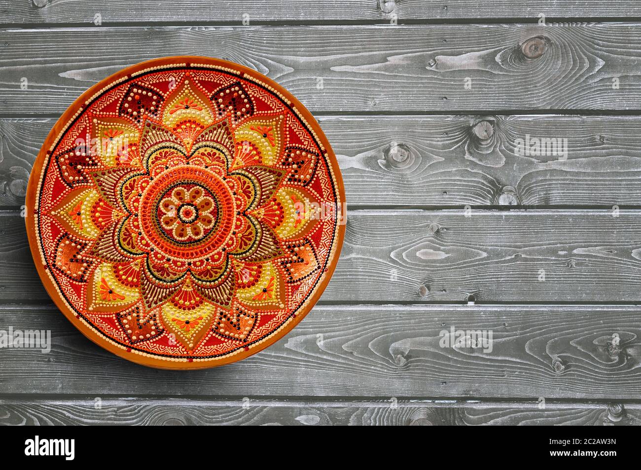 Dekorative Keramikplatten handbemaltes Punktmuster mit Acrylfarben auf grauem Holzhintergrund. Speicherplatz kopieren. Stockfoto