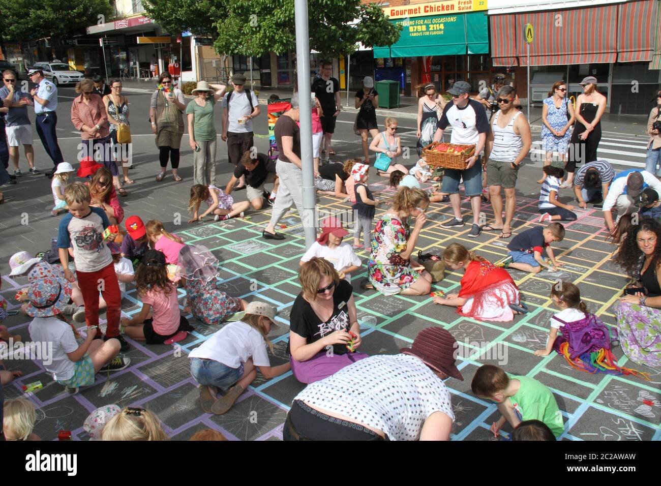 Kinder zeichnen mit Kreide Bilder und schreiben Botschaften innerhalb der Regenbogenkreuzung an der Lackey Street, Summer Hill, bei ihrer offiziellen Markteinführung. Stockfoto