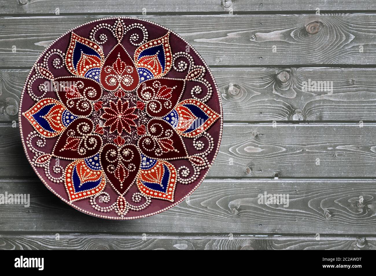 Dekorative Keramikplatten handbemaltes Punktmuster mit Acrylfarben auf grauem Holzhintergrund. Speicherplatz kopieren. Stockfoto