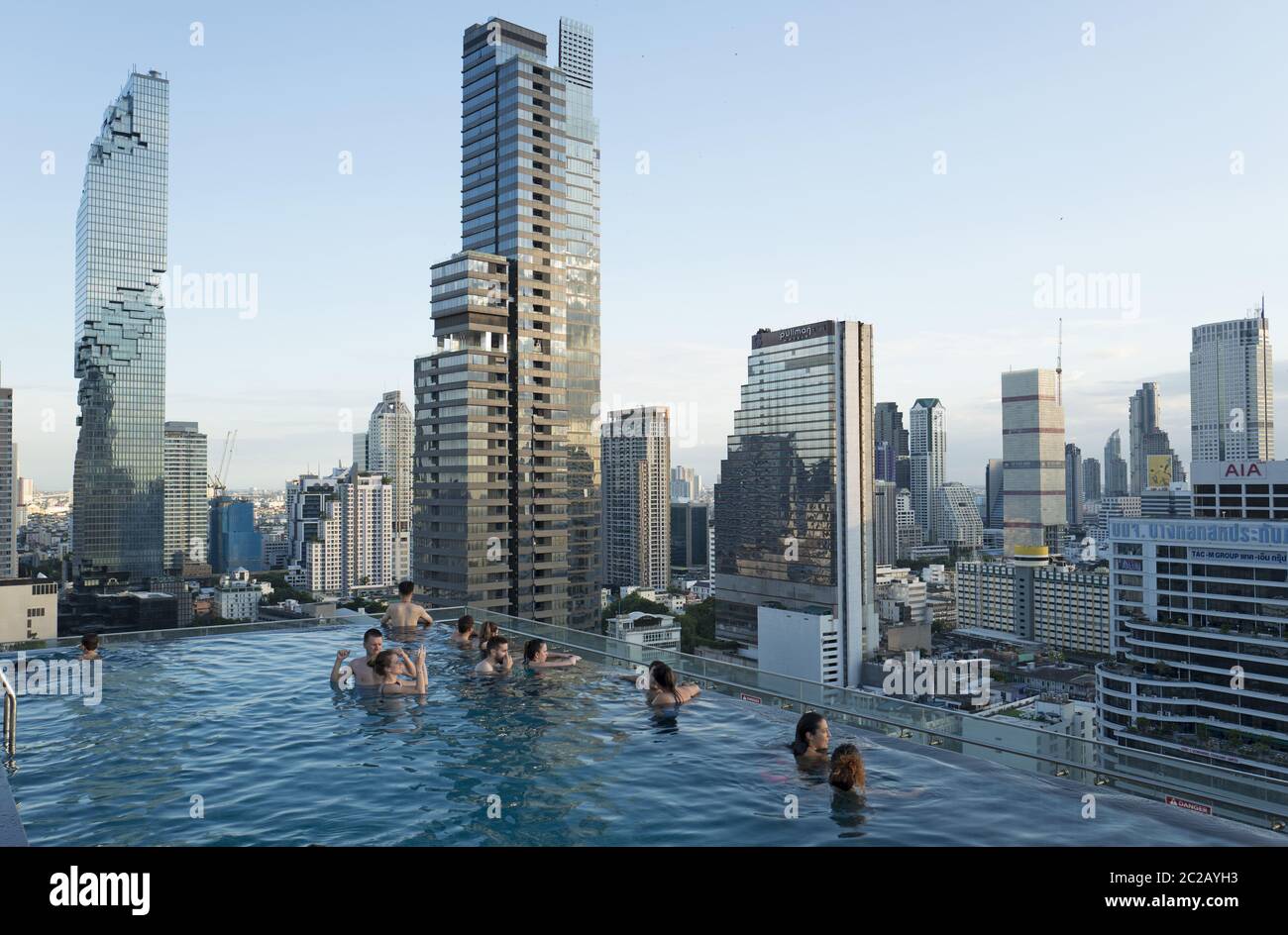 Junge Menschen genießen den Sonnenuntergang über den Wolkenkratzern der Stadt, von einem Dach Infinity-Pool, in Bangkok. Stockfoto