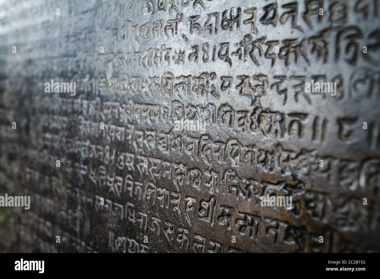 Religiöse asiatische nepalesische Schriften tief in einer dunklen Steinwand in einem Schrein geschnitzt. Kathmandu, Nepal, Asien Stockfoto