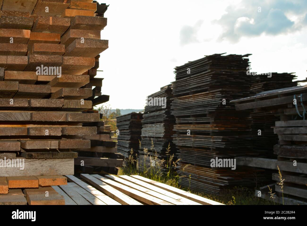 Gestapelte Holzbretter in einem Sägewerk Lager mit bewölktem Himmel Stockfoto