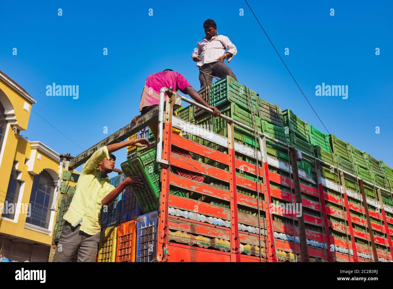 Mitarbeiter einer Spedition, die einen LKW vor einem tiefblauen, sonnigen Himmel verladen; Mumbai, Indien Stockfoto