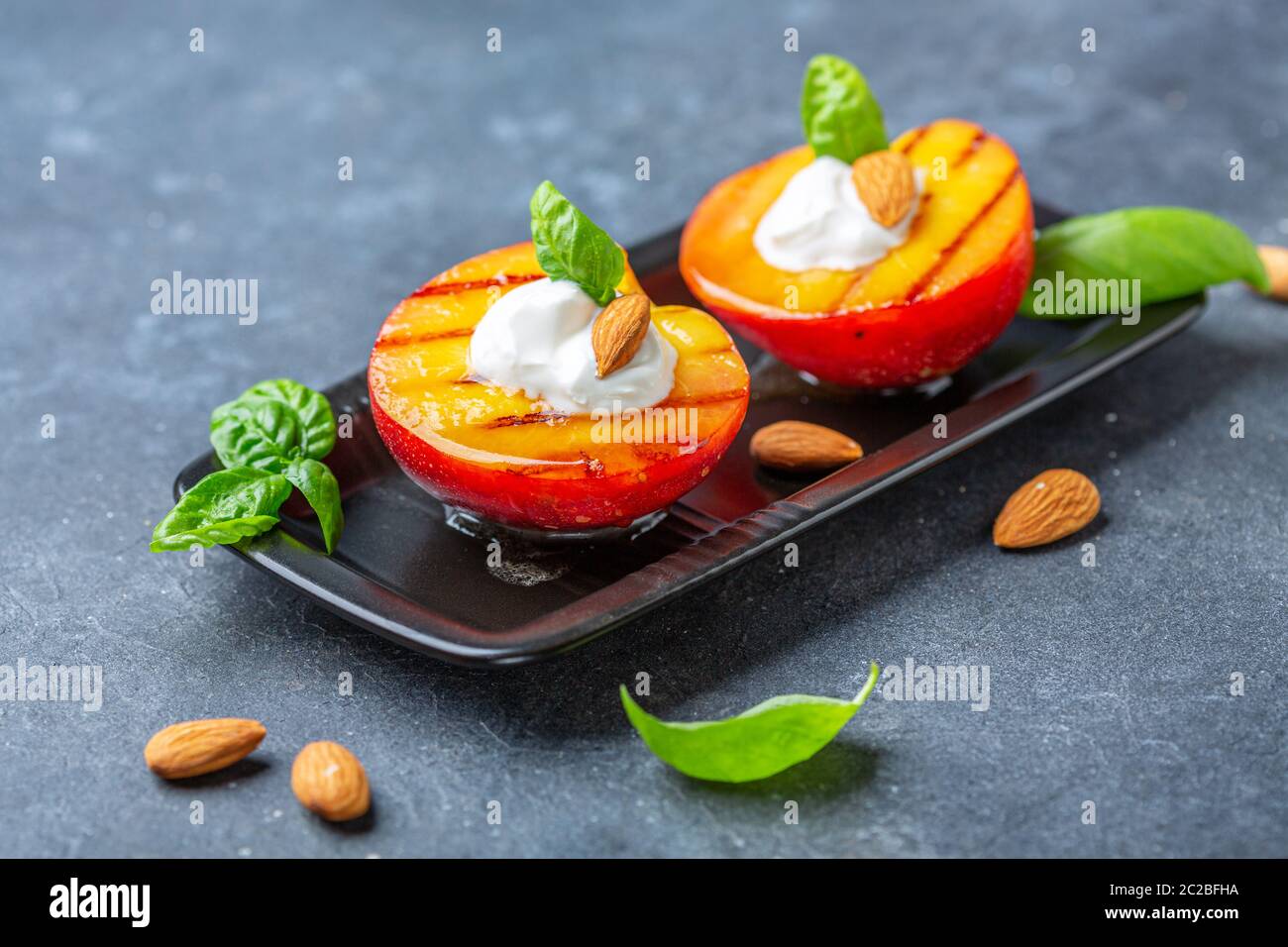 Gegrillter Pfirsich mit Honig, Joghurt und Mandeln. Stockfoto