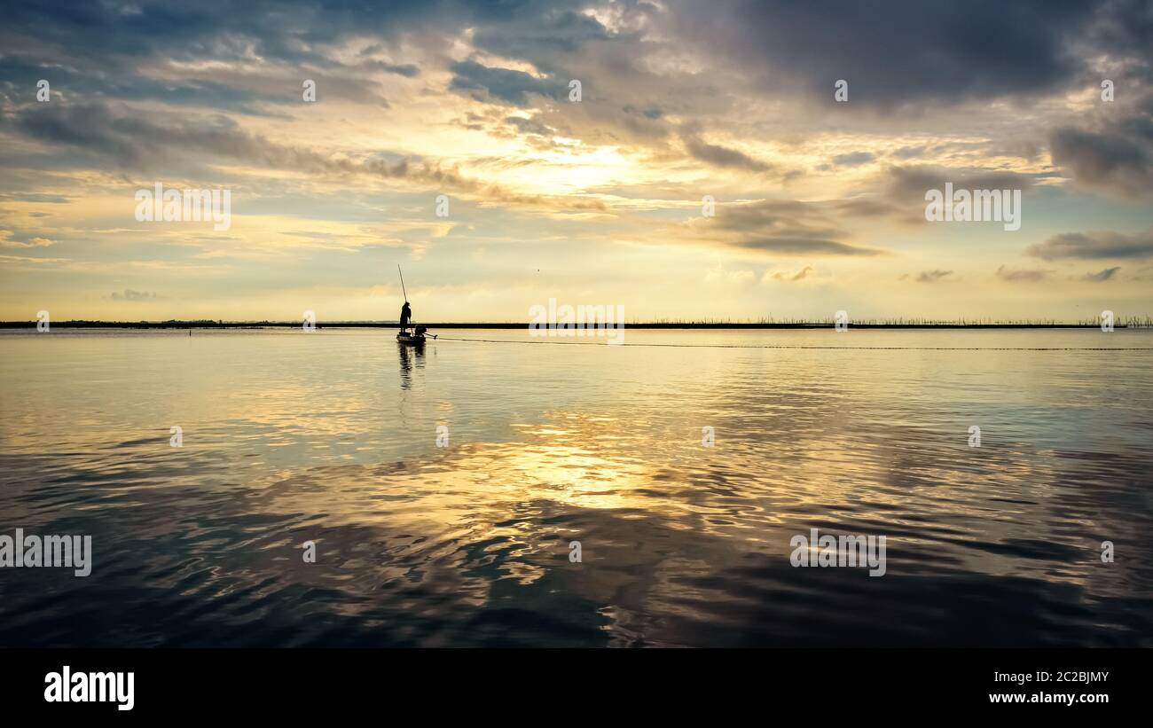 Fischer auf dem Boot verwenden Fischernetze bei Sonnenaufgang, Thailand Stockfoto