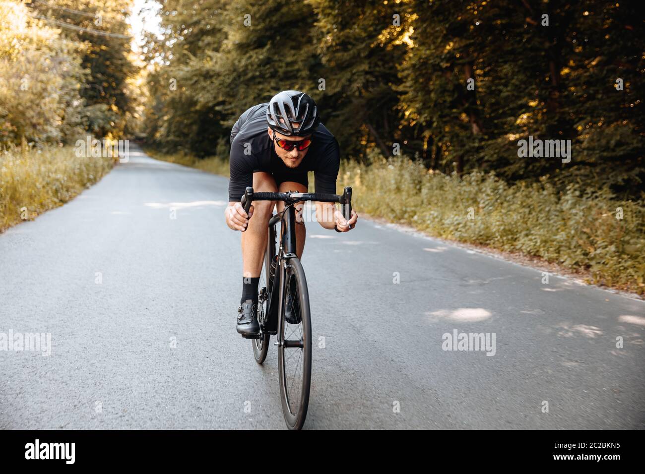 Sportlich bärtiger Mann in Schutzhelm und Spiegelbrille Reiten Fahrrad in halb-gebogen Pose für bessere Geschwindigkeit. Profi-Sportler in aktiver Kleidung Pre Stockfoto