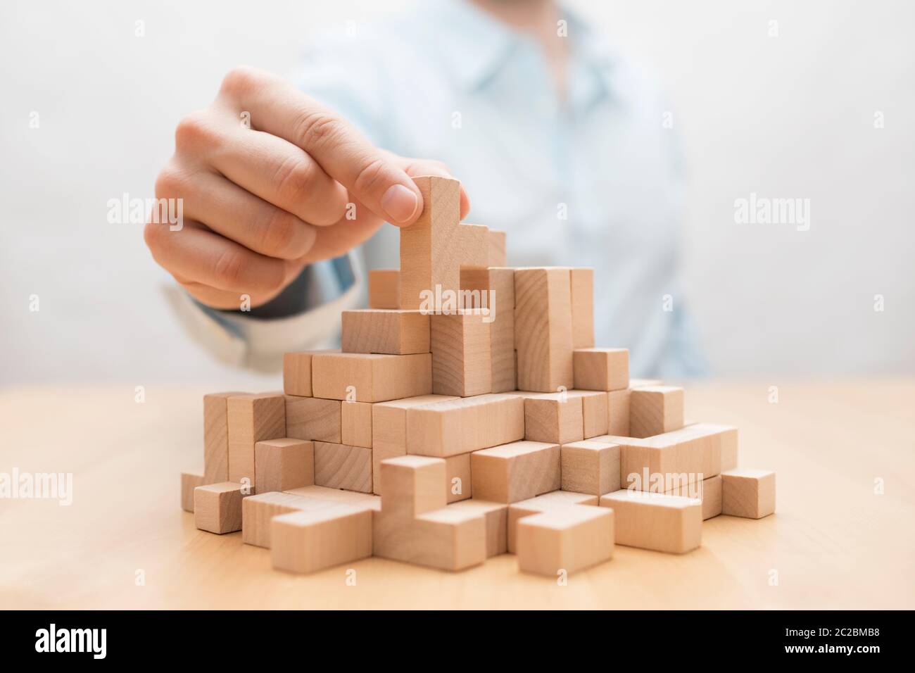Des Menschen Hand stapeln Holz- Bausteine. Business Development Konzept Stockfoto