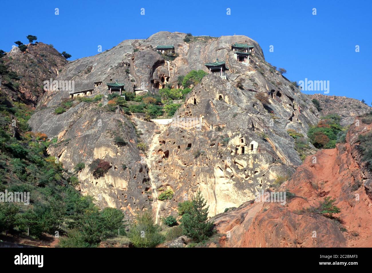 Blick auf die Xumishan Grotten, die auch als Xumi Shan oder Xumishan bezeichnet werden. Sie sind eine Sammlung von über 130 buddhistischen Höhlentempeln, die in eine rote Sandsteinklippe in der autonomen Region Ningxia Hui im Nordwesten Chinas gehauen wurden Stockfoto