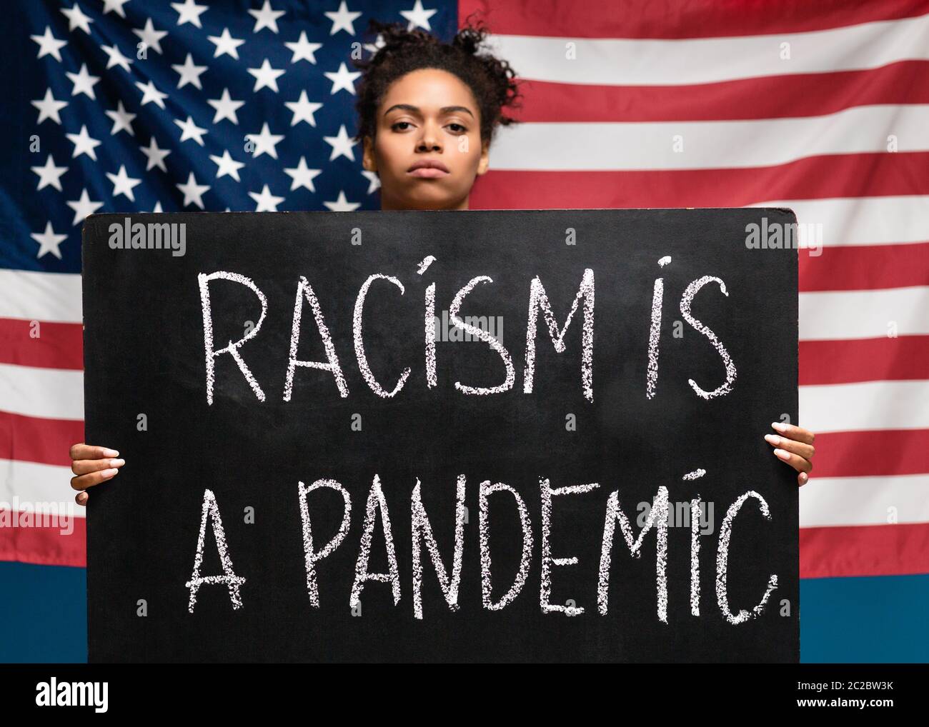 afroamerikanische Frau mit Plakat Rassismus ist eine Pandemie Stockfoto