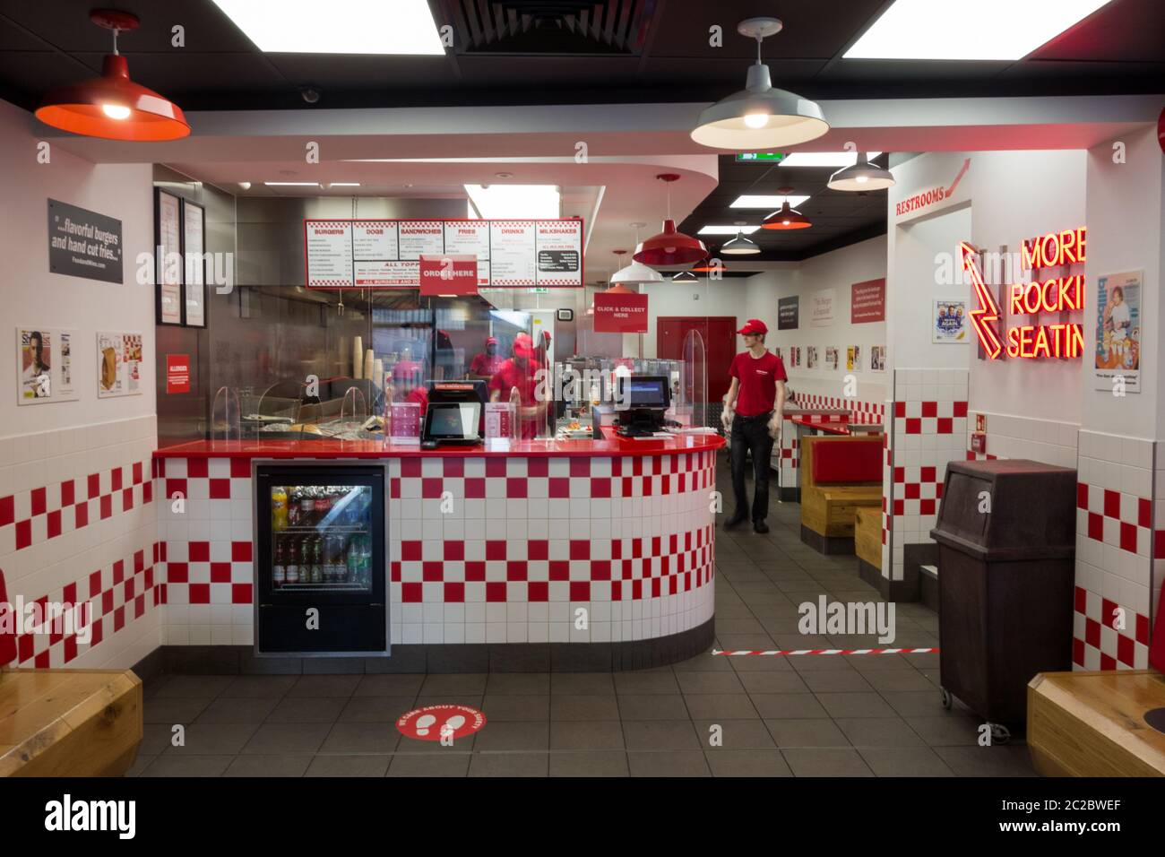 Soziale Distanzierungsschilder und Mitarbeiter hinter dem Schalter in einem 5-Jungs-Fast-Food-Restaurant in London, England, Großbritannien Stockfoto