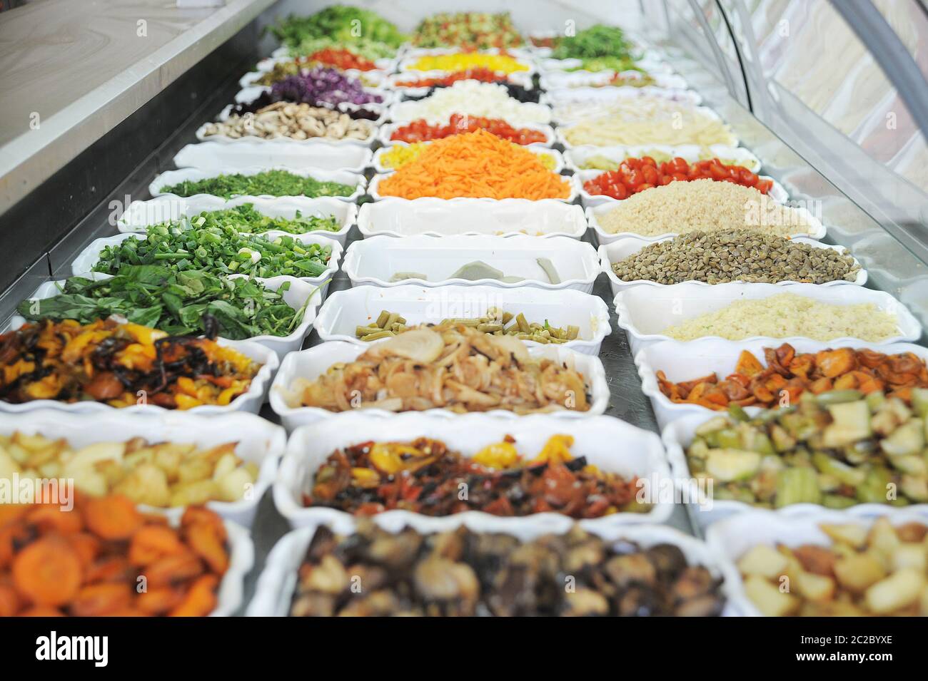 Schneiden Sie die Zutaten für den Salat an einer Salatbar Stockfoto