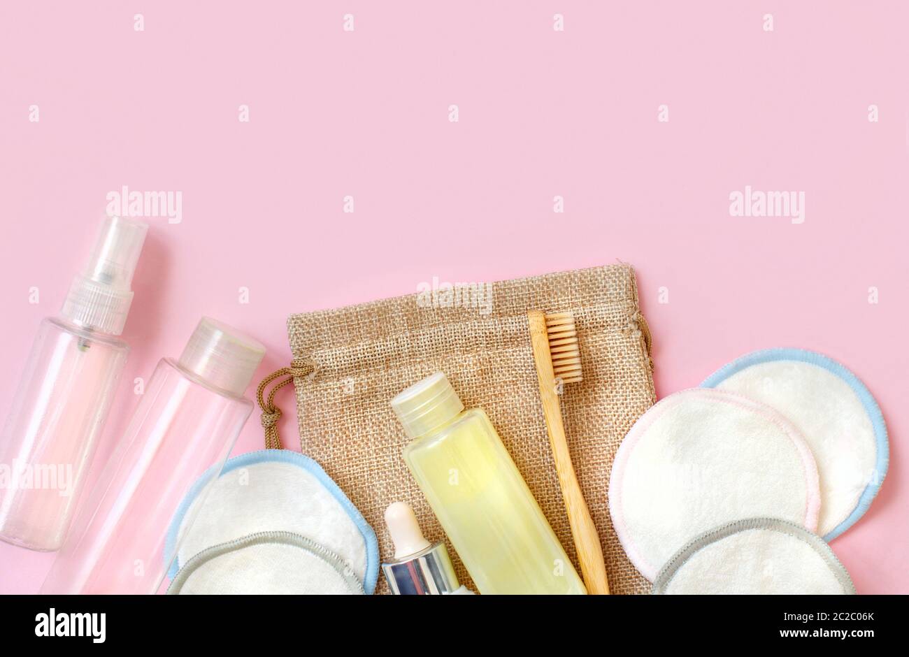 Bambus Zahnbürste, Make-up Entferner Pads und Flüssigkeit, Shampoo, Handtuch auf rosa Hintergrund Draufsicht Stockfoto