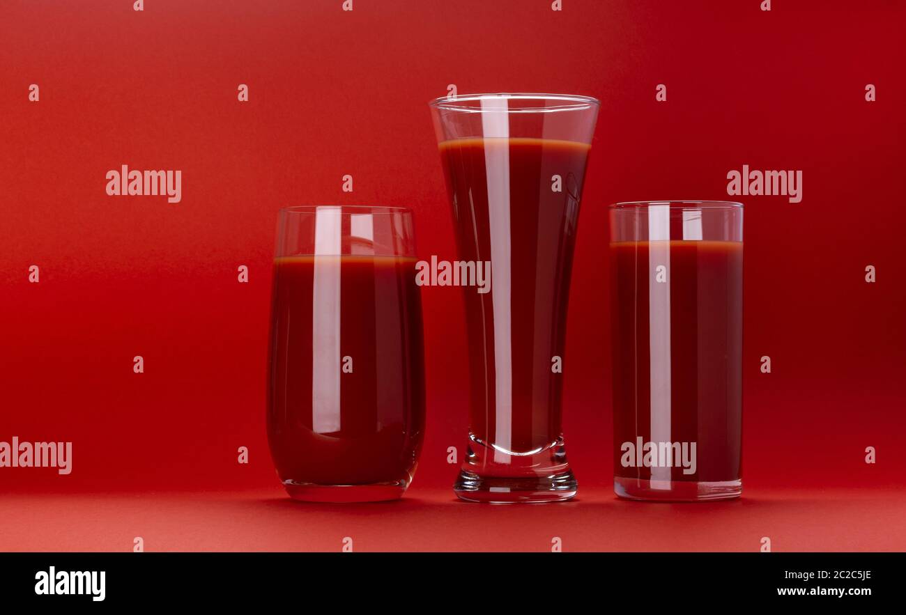 Glas Tomatensaft isoliert auf rotem Hintergrund mit Kopierraum Stockfoto