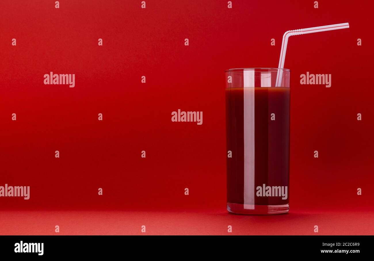 Glas Tomatensaft auf rotem Hintergrund isoliert Stockfoto