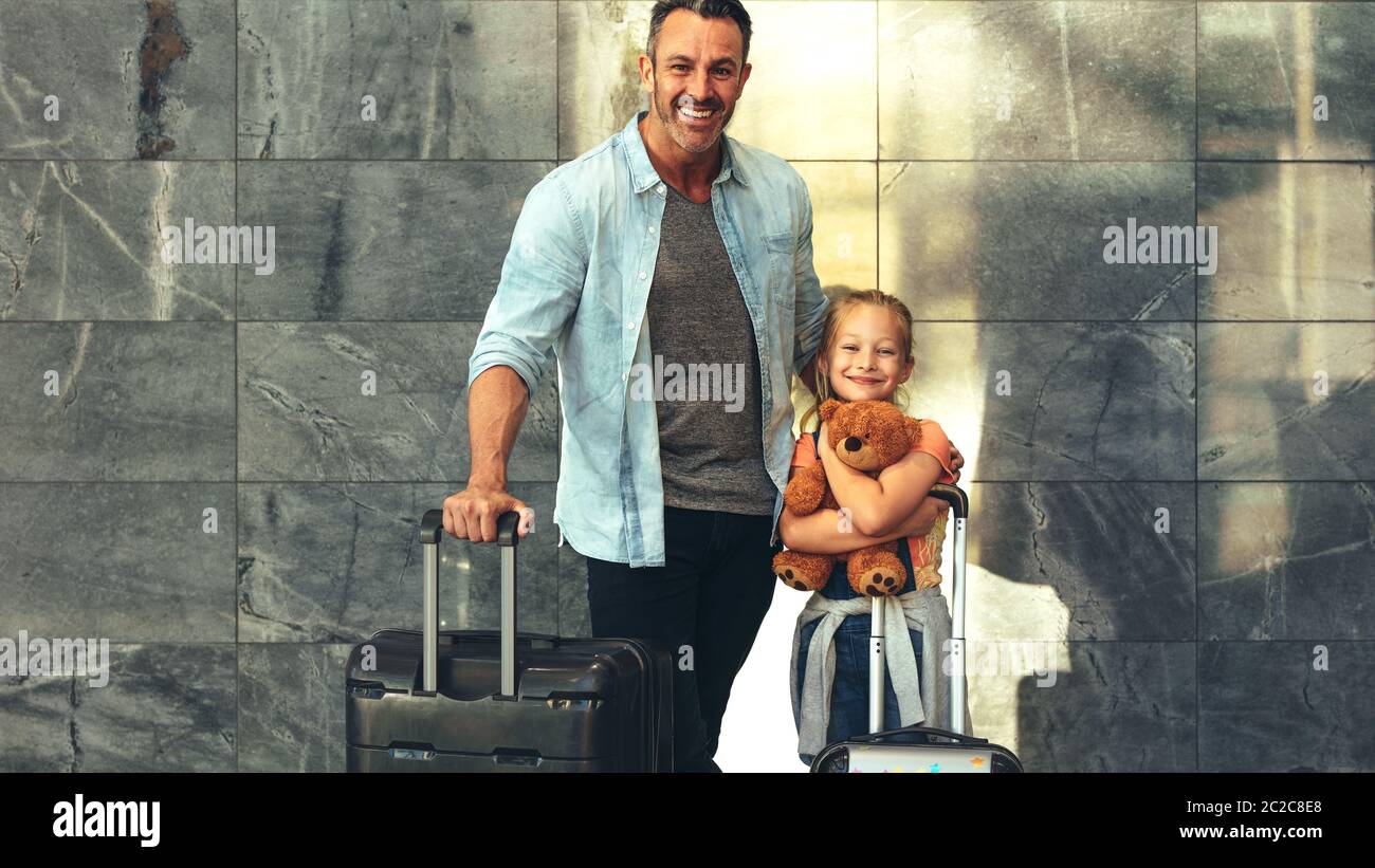 Vater und Tochter stehen zusammen mit ihrem Gepäck am Flughafen. Die zweiköpfige Familie reist zusammen, schaut auf die Kamera und lächelt. Mann mit einem Reisenden Stockfoto Vater und Tochter stehen zusammen mit ihrem Gepäck am Flughafen. Die zweiköpfige Familie reist zusammen, schaut auf die Kamera und lächelt. Mann mit einem Reisenden Stockfoto