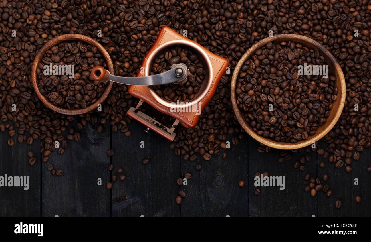 Gemahlener Kaffee, Kaffee Mühle, Schüssel gerösteten Kaffeebohnen auf schwarzem Holz- Hintergrund, Ansicht von oben Stockfoto