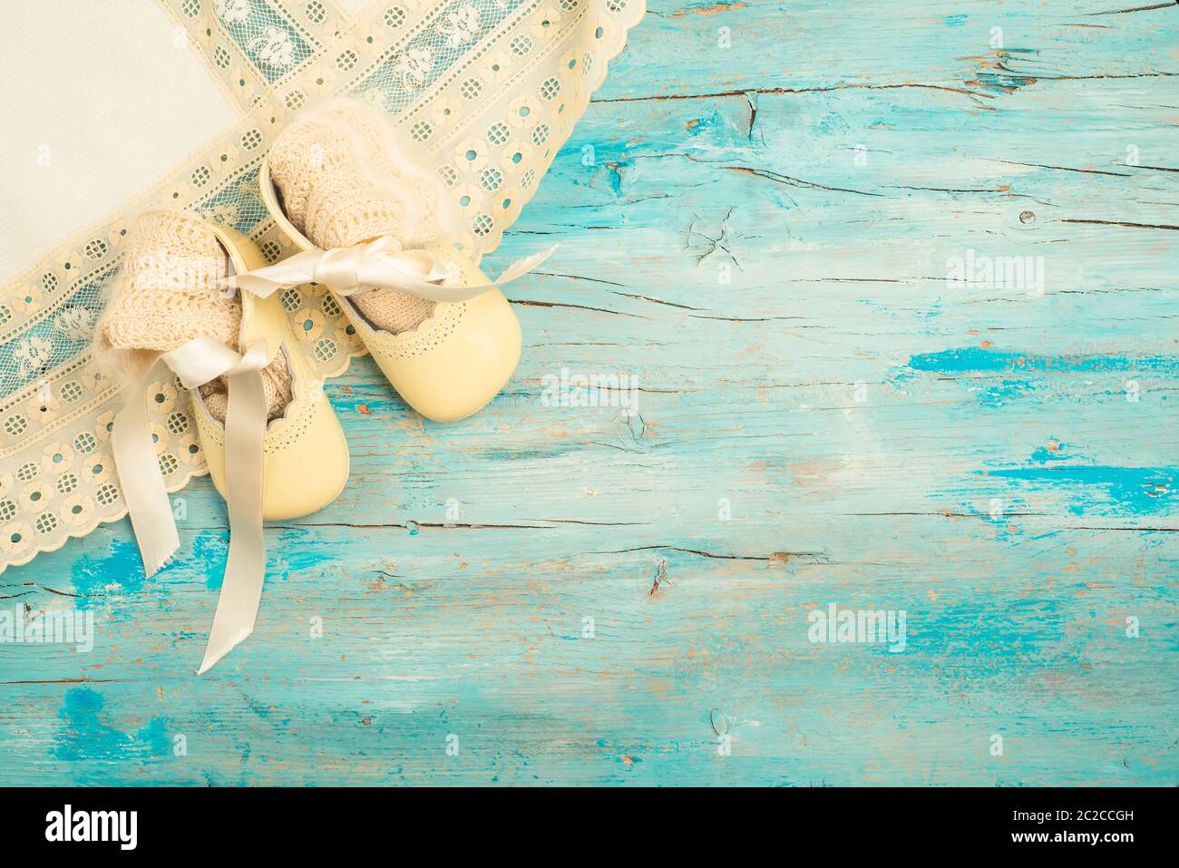 Traditionelle Babykleidung, Stiefelette, Taufrock und handgefertigte Perlen- und Angorasocken auf blauem Holz, neugeborenes Kind. Stockfoto