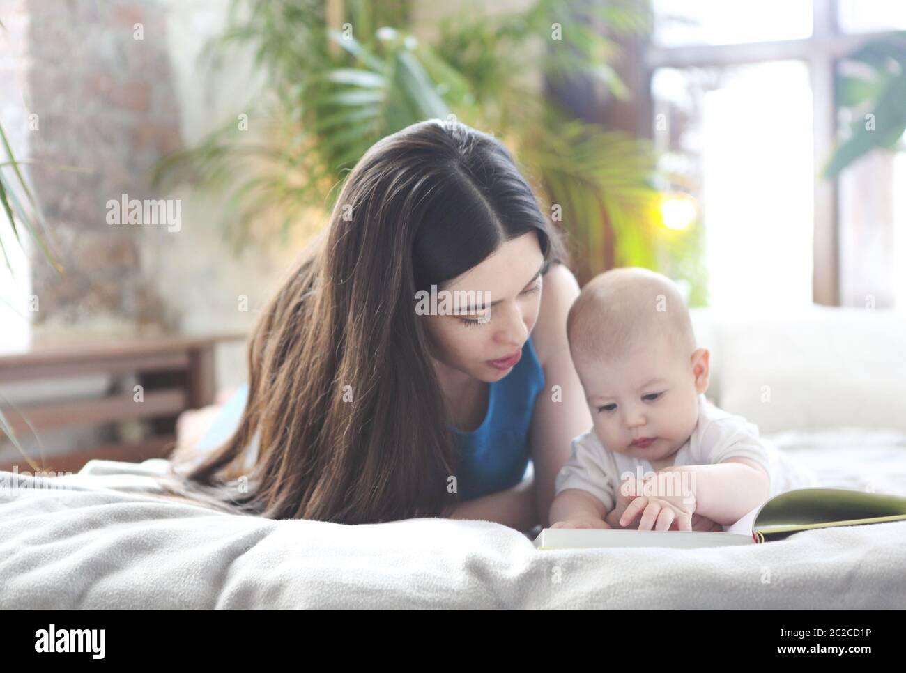 Mutter liest ein Buch mit ihrem kleinen Sohn im Schlafzimmer Stockfoto