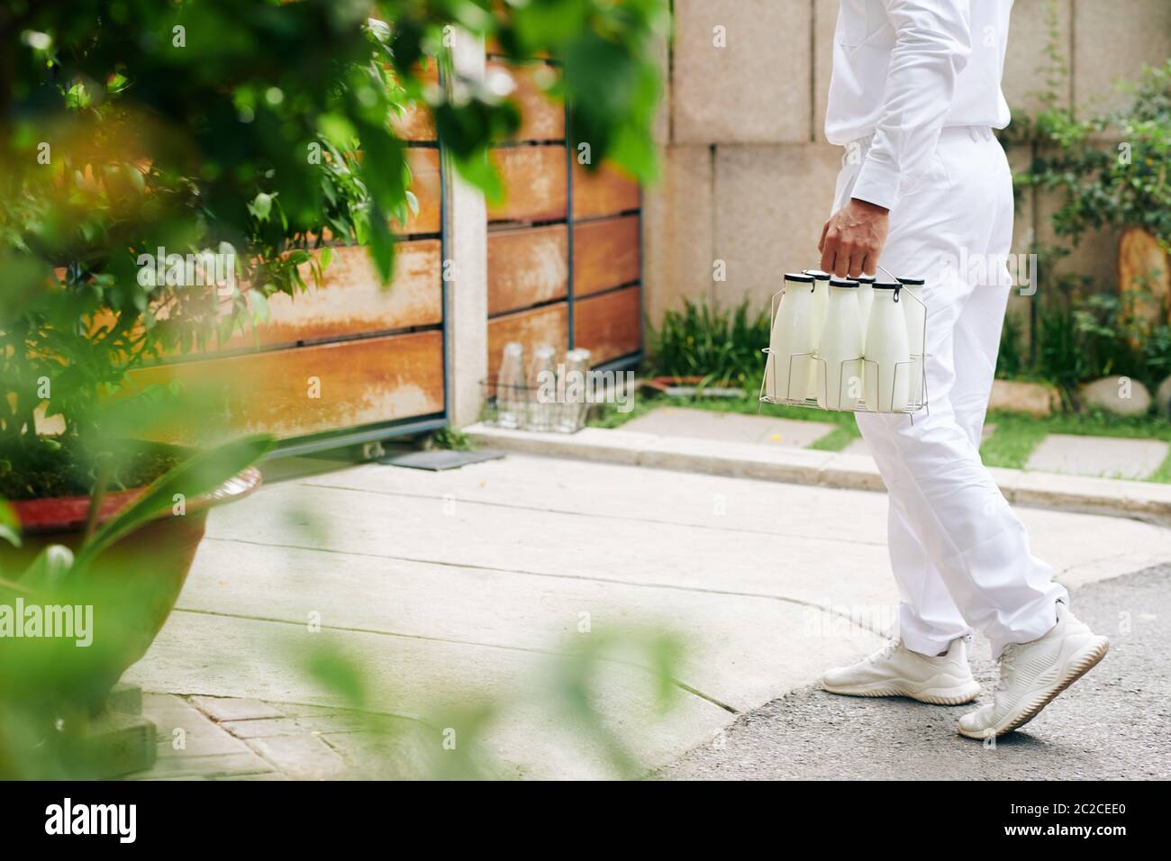 Unerkennbarer Milchmann in weißer Uniform, der seinen Kunden Milch liefert und morgens leere Glasflaschen zurücknimmt, Platz kopiert Stockfoto