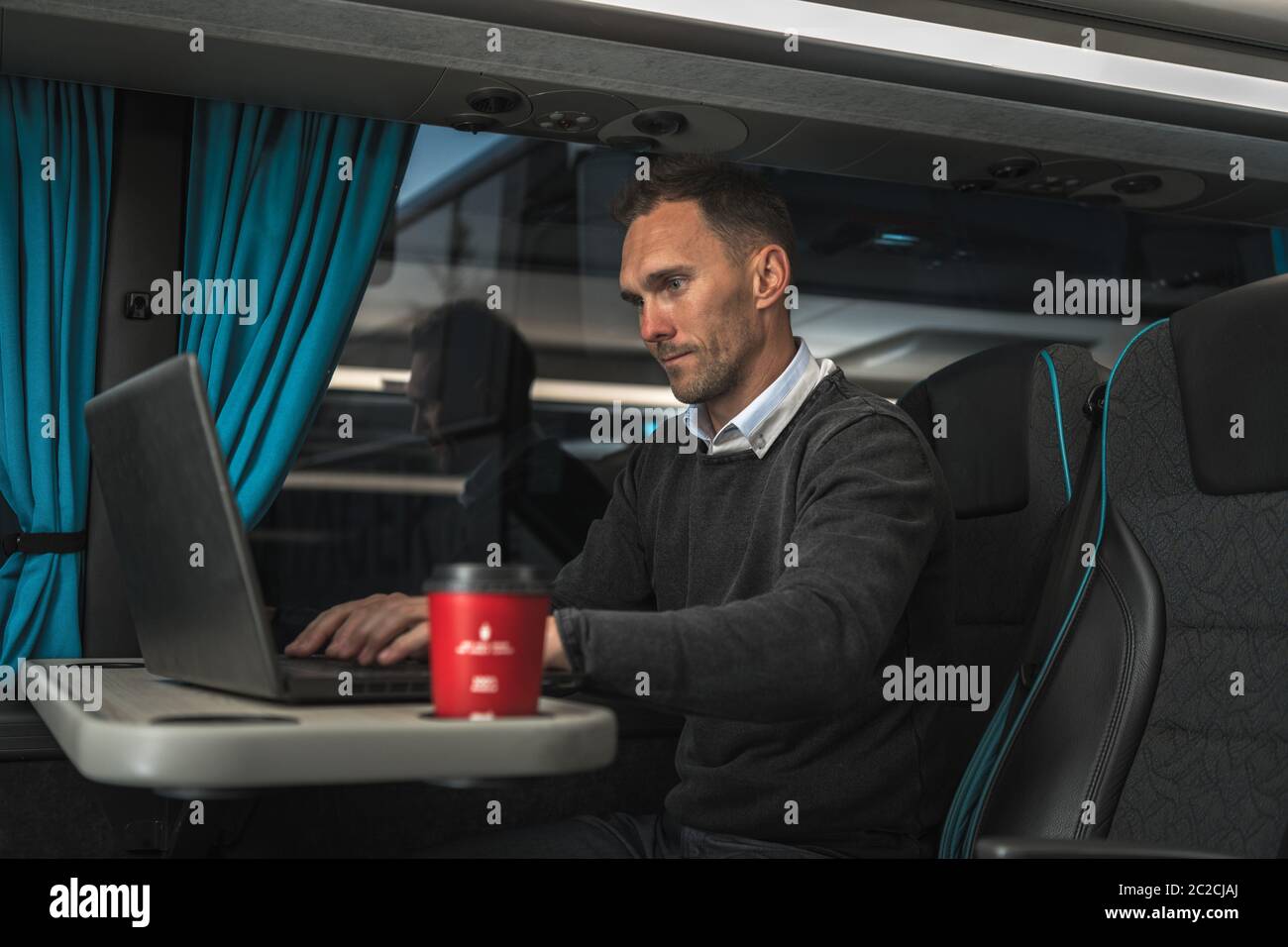 Kaukasischen Geschäftsmann in seinen 40er Jahren arbeitet auf seinem Laptop innerhalb Bus auf Langstrecke. Arbeiten Auf Reisen Konzeptfoto. Stockfoto