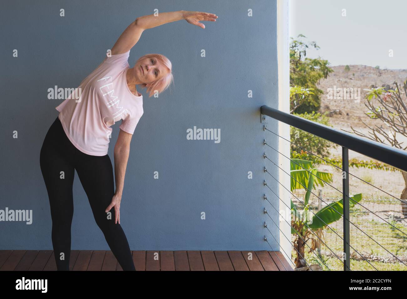 Ältere Frau, die fit bleibt und zu Hause Strecken auf Deck macht Stockfoto