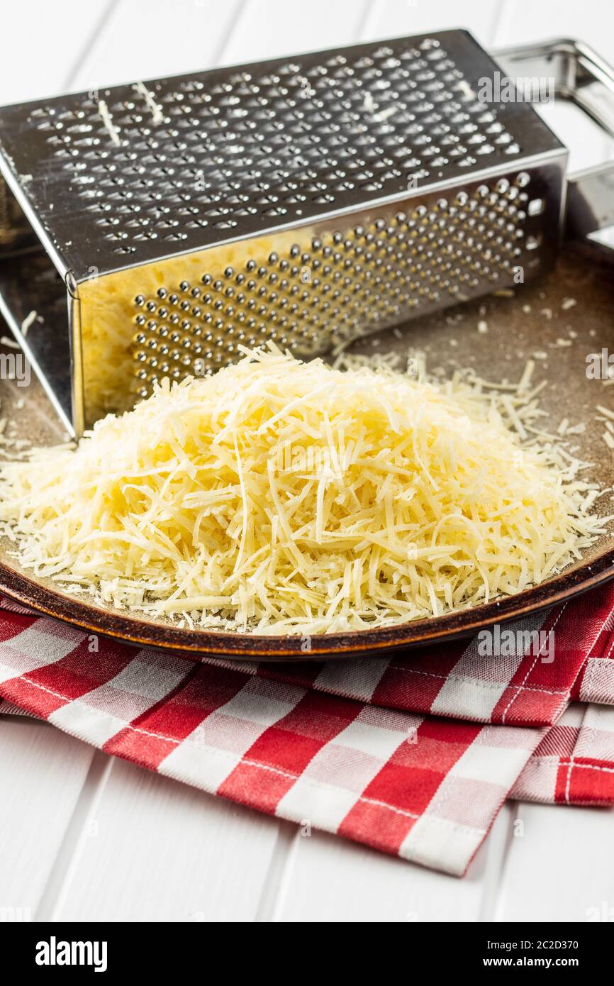 Leckere geriebener Käse. Parmesan mit REIBE an der Platte. Stockfoto