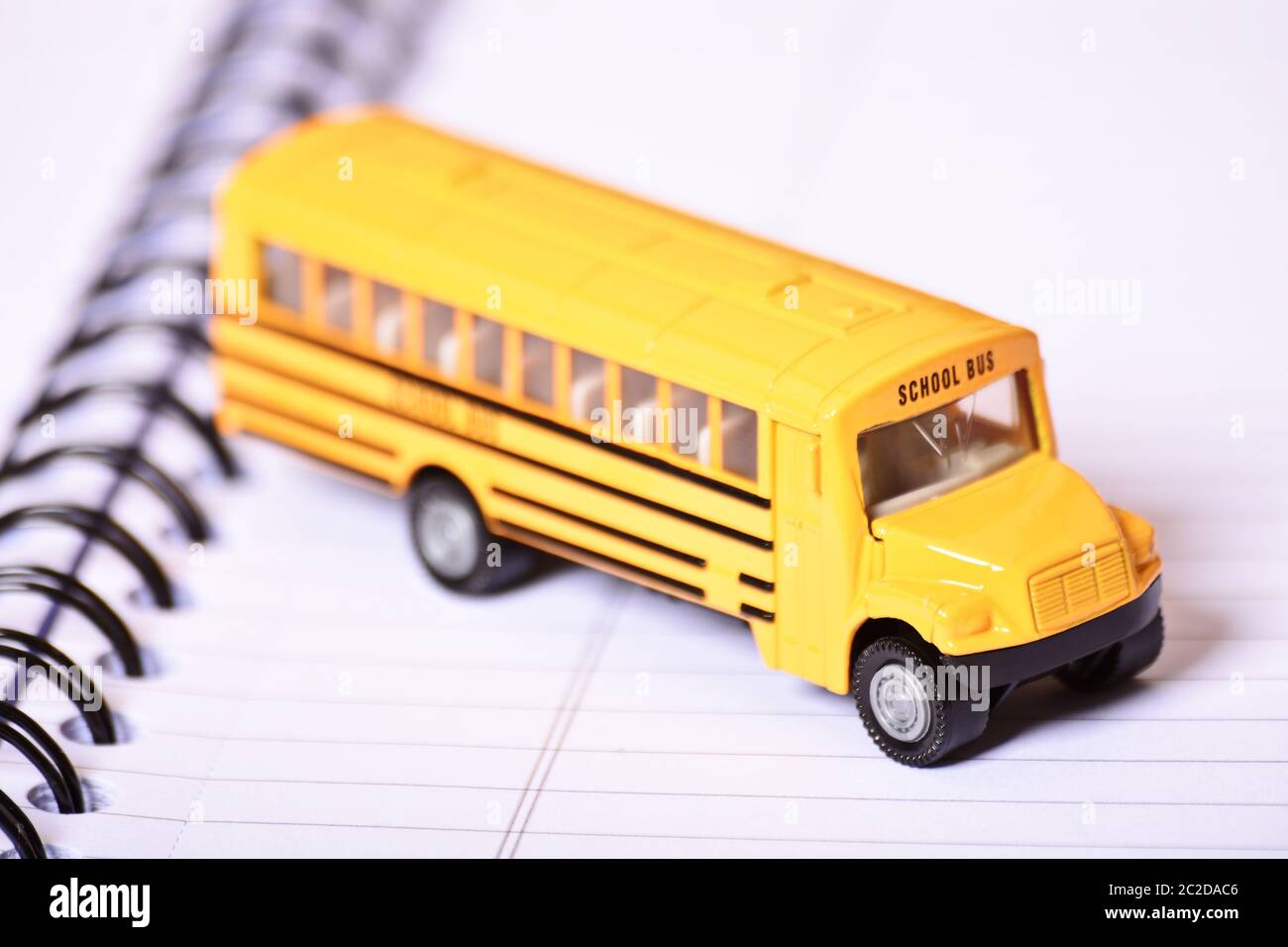 Nahaufnahme von einem Spielzeug Schulbus auf offene Spirale notebook. Stockfoto