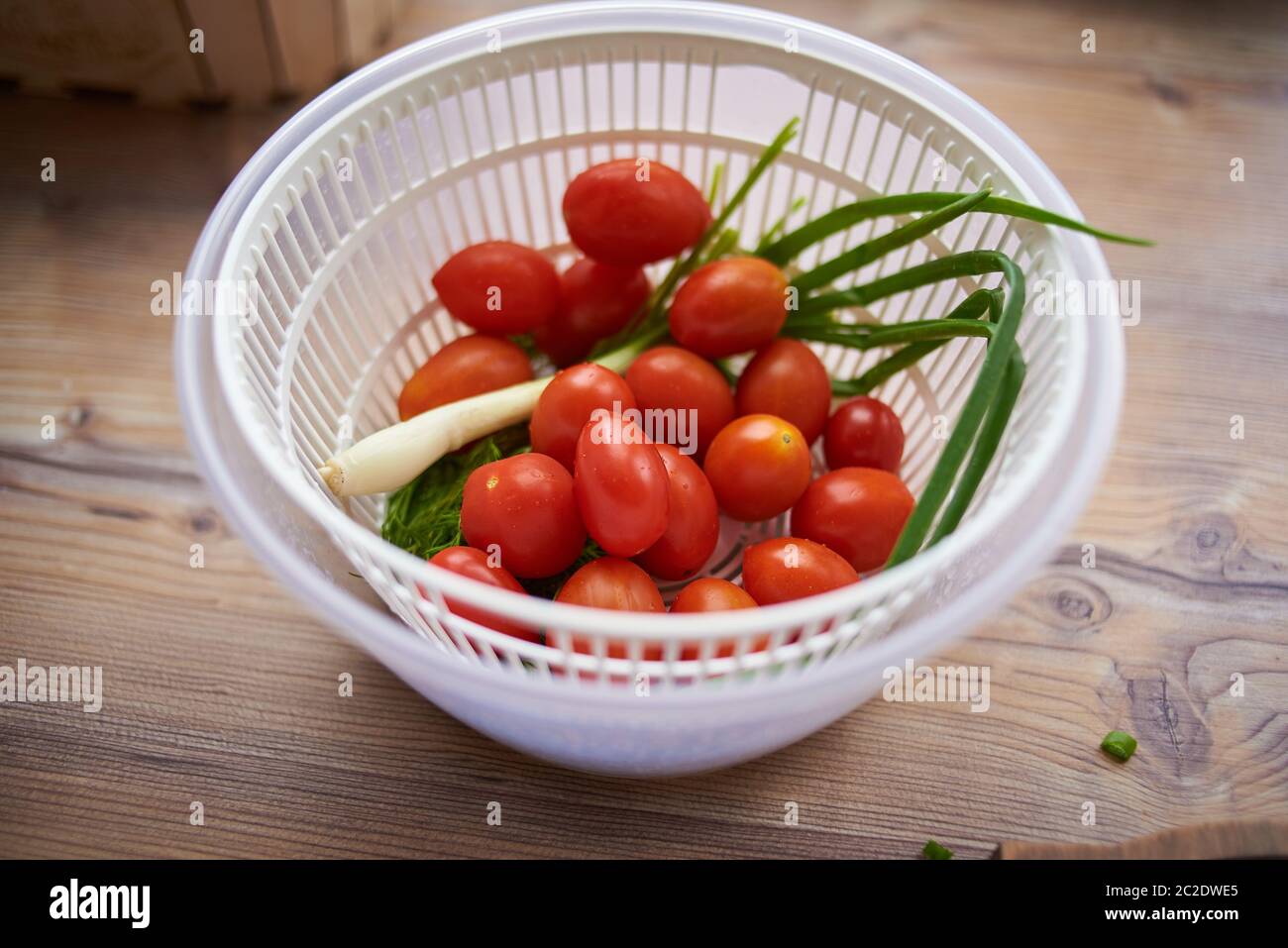 Ein Mann wäscht, reinigt und schneidet Gemüse. Tomaten, Knoblauch, Kräuter Stockfoto