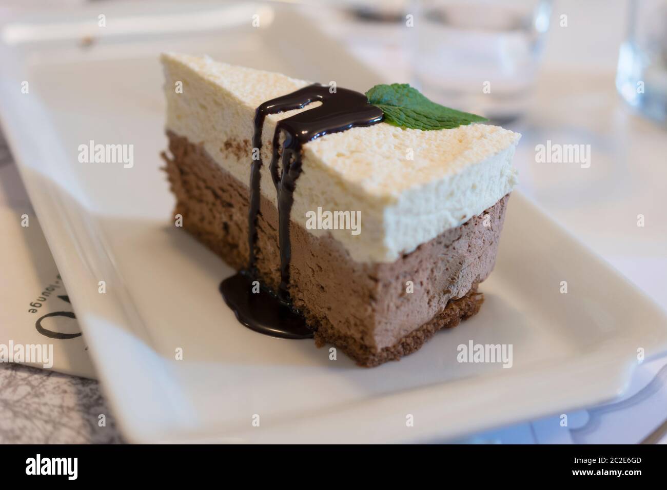 Scheibe von köstlichem Schokoladenmousse mit weißer und schwarzer Schokolade, Biskuitkuchen und dunkler Schokoladenglasur Belag Stockfoto