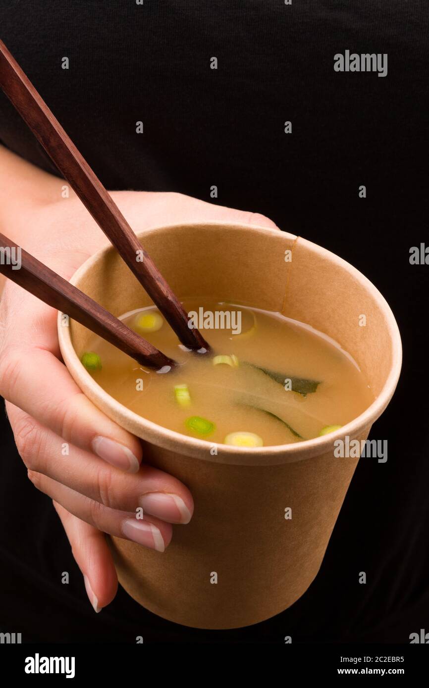 Schöne Mädchen, dass Miso Suppe mit Tofu und Algen im Takeaway Cup. Der traditionellen asiatischen Küche. Stockfoto
