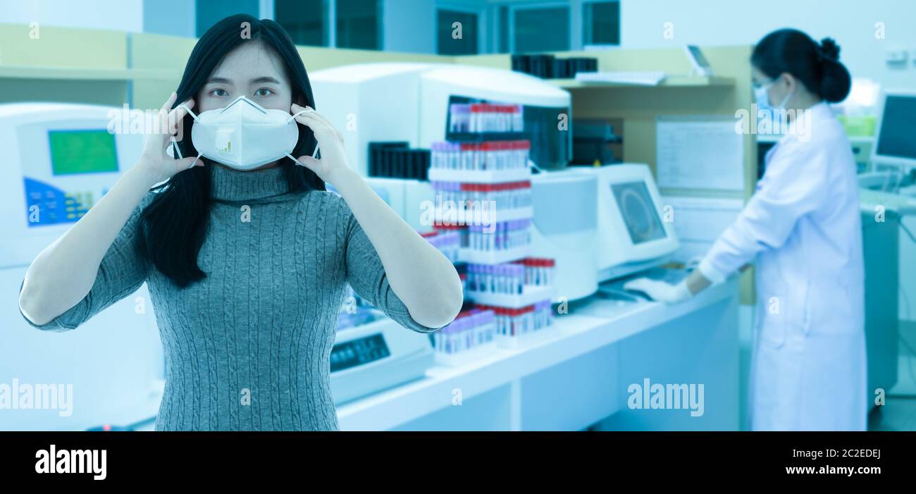 Junge Frau trägt Schutz Gesichtsmaske mit Gesundheitsforschern arbeiten in Life Science Labor, Medical Corona Virus Konzept Stockfoto
