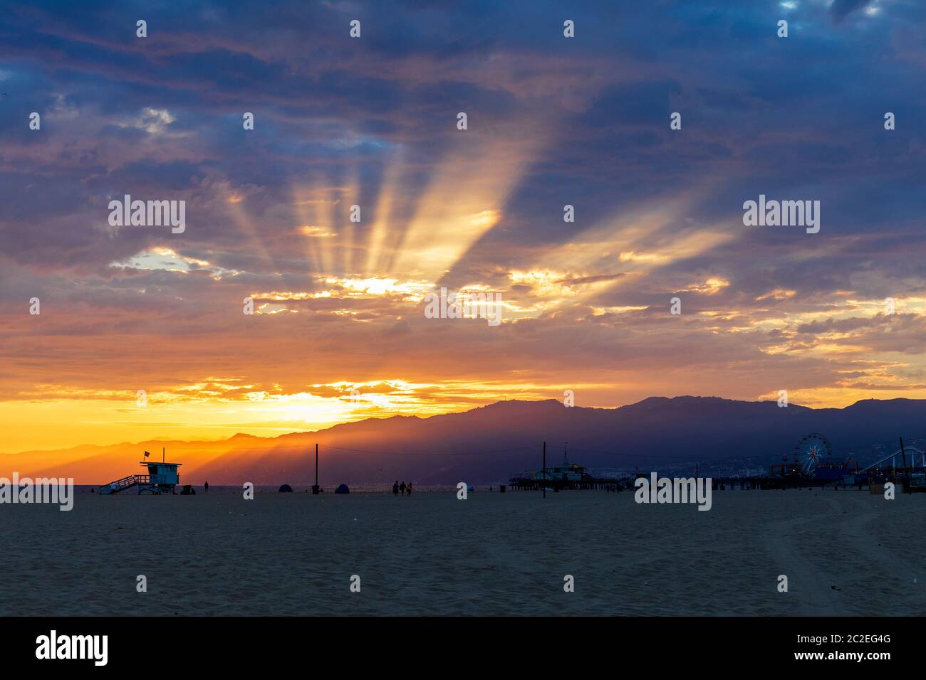Wunderschöner Sonnenuntergang hinter den Santa Monica Bergen mit dem Santa Monica Pier und Strand im Vordergrund. Stockfoto