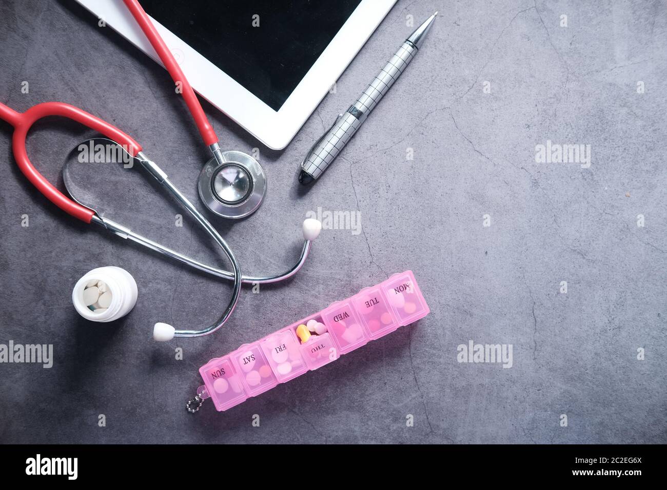 Medizinisches Stethoskop, Pillen und digitales Tablet auf schwarzem Hintergrund Stockfoto