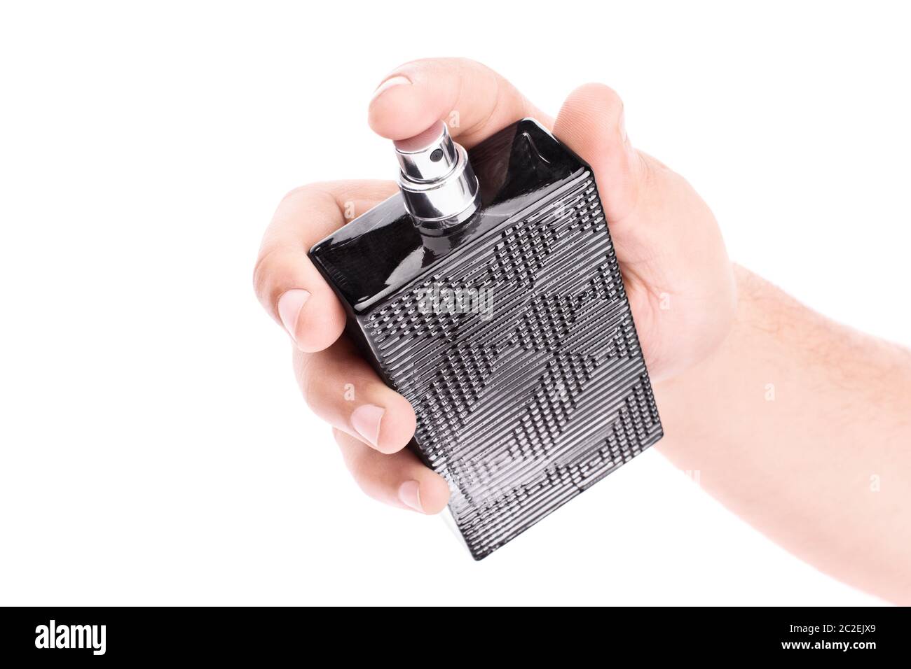 Nahaufnahme einer männlichen Hand, die eine unbeschriftete schwarze Parfümflasche auf weißem Hintergrund isoliert hält. Stockfoto