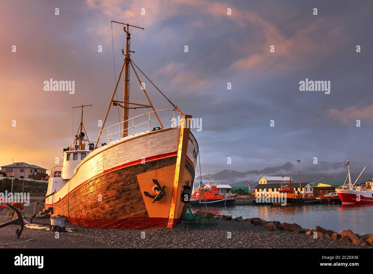 Dramatischer Sonnenuntergang über dem Hafen von Hofn im Südosten Islands. Die Komposition konzentriert sich auf das Schiffswrack eines alten Fischerbootes, heute decora Stockfoto