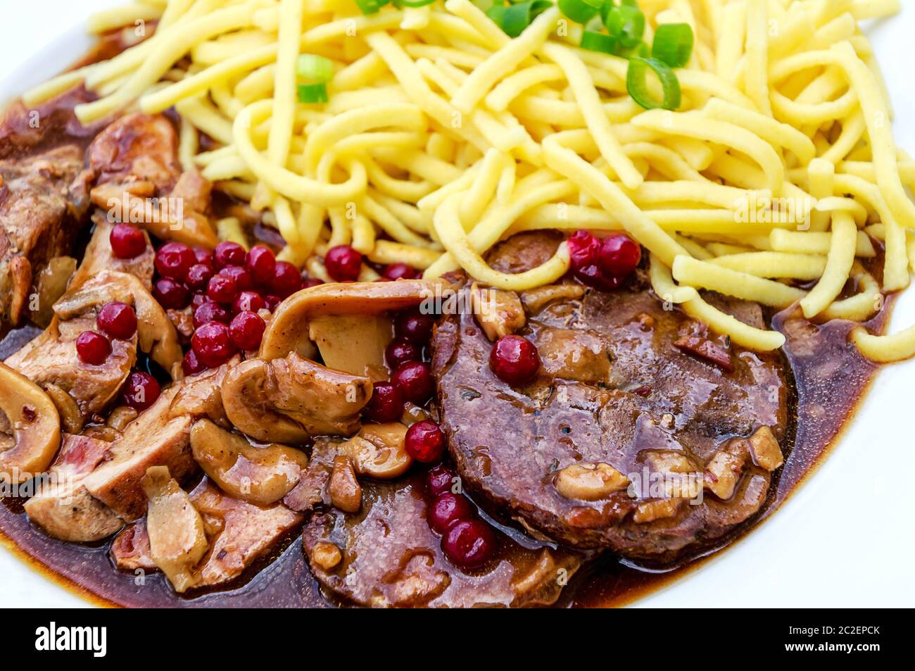 Gebratene Reh und Wildschwein mit Preiselbeeren und hausgemachten Spätzle Stockfoto