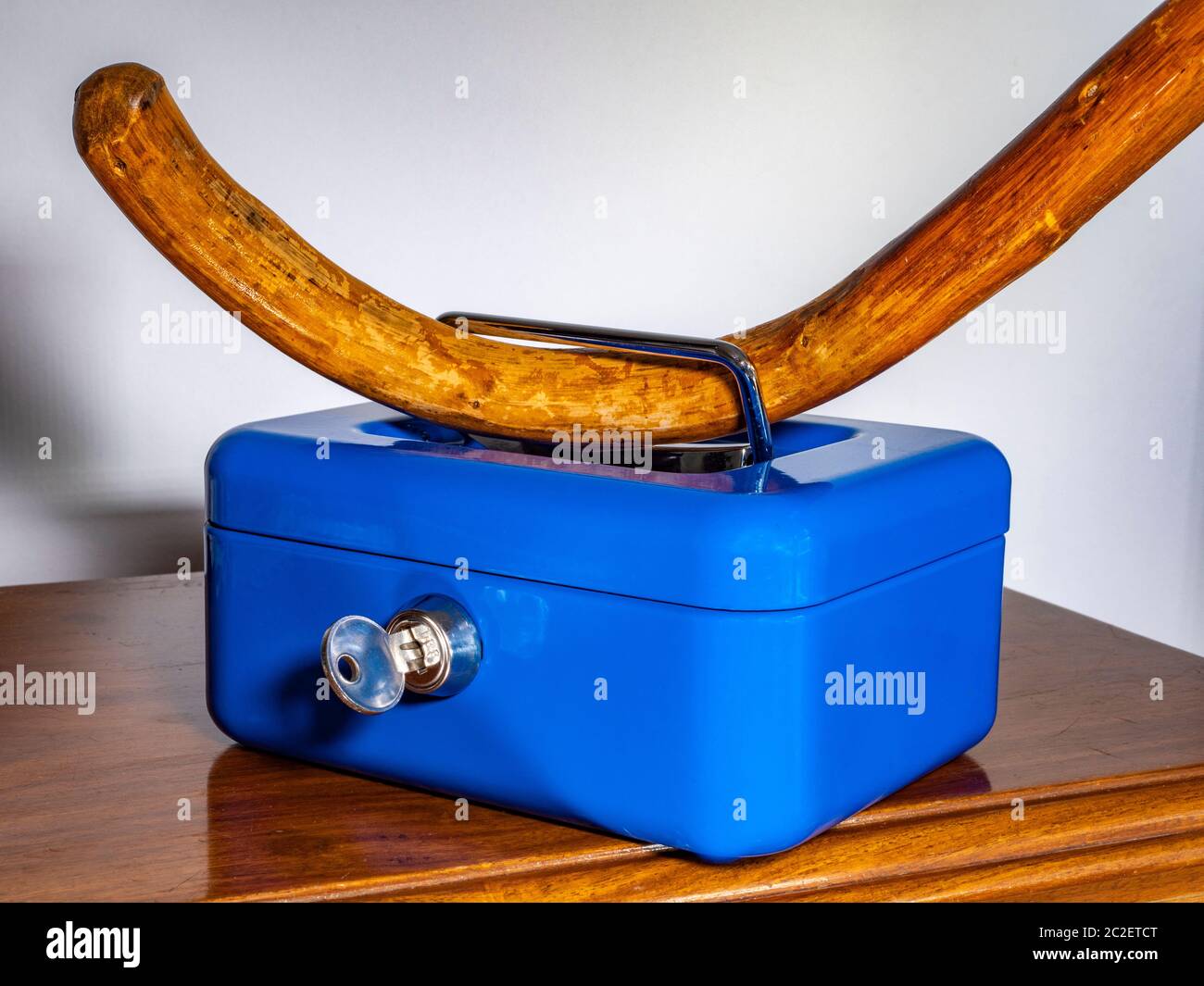 Gehstock durch den Griff der verschlossenen Metallbox im Regal – Sicherheitskonzept (Geld, Dokumente, kleine Wertsachen) in Bezug auf ältere Menschen. Stockfoto