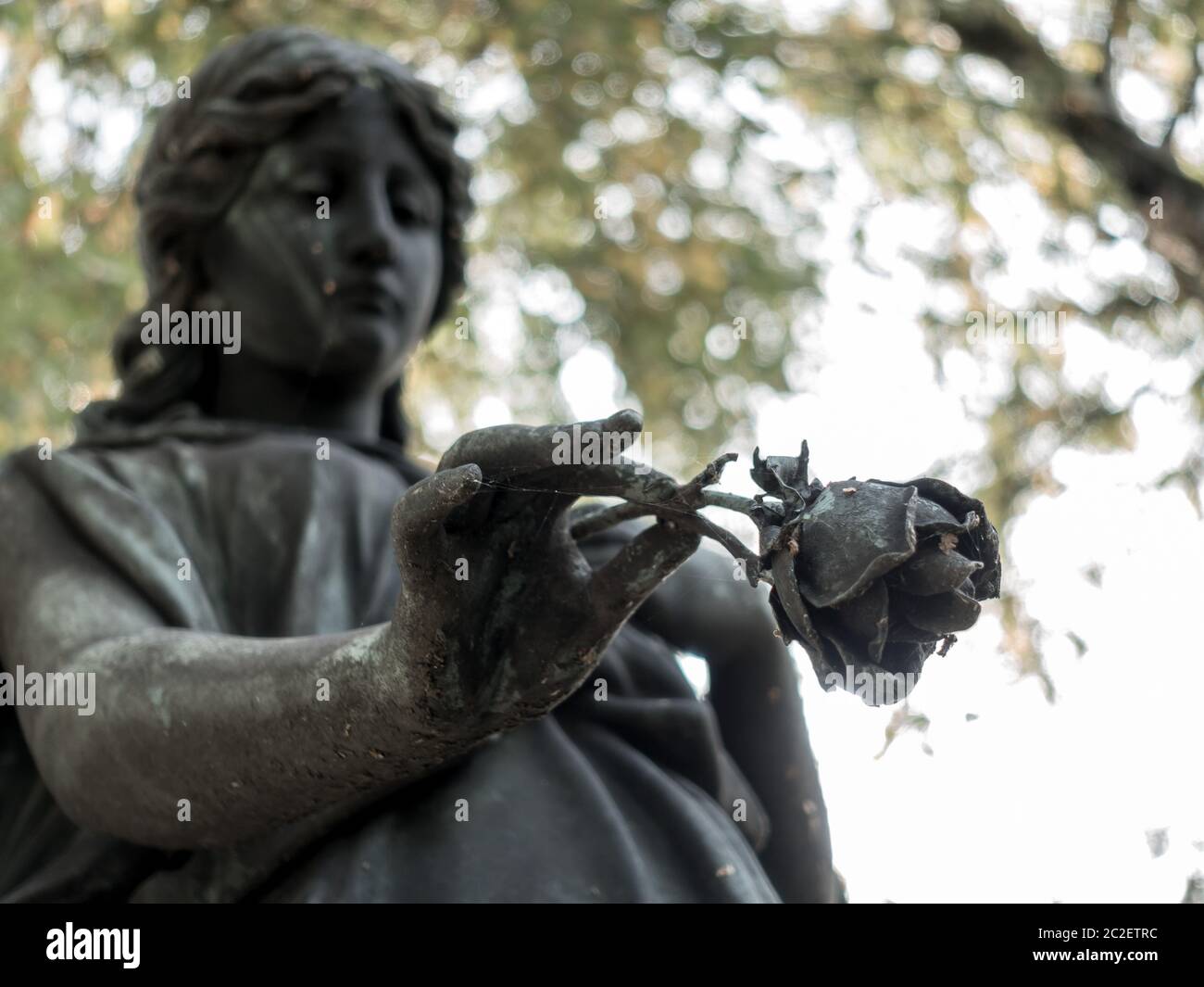 Ein Engel auf einem Friedhof hält eine Abschiedsrose in der Hand Stockfoto
