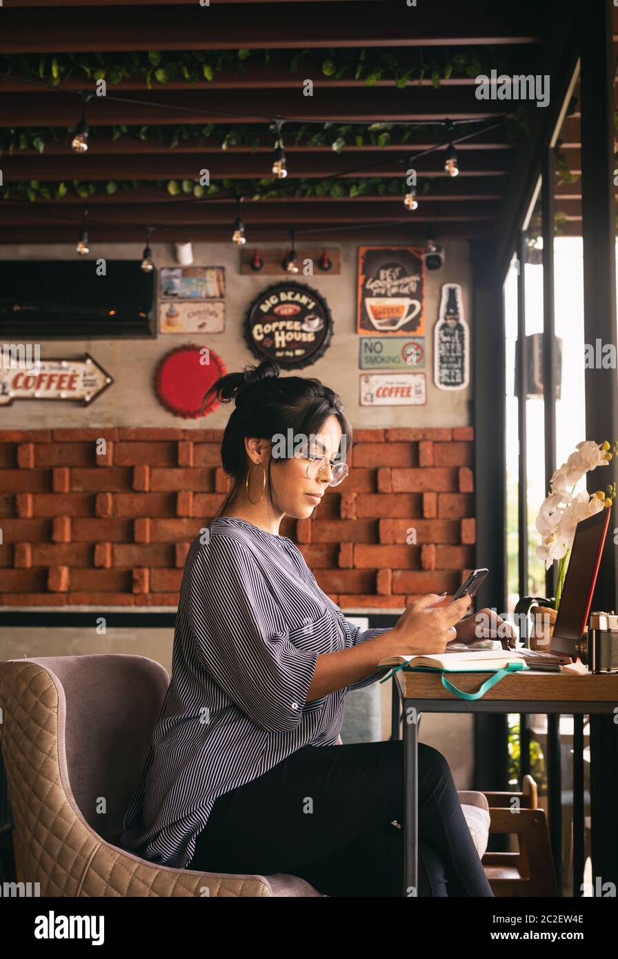 Frau, die beim Kaffee arbeitete und ihr Handy überprüfte Stockfoto