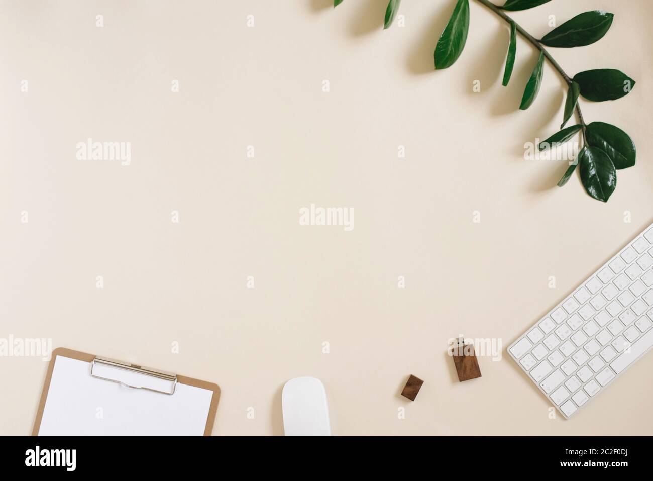 Moderner Desktop eines Freelancers oder Bloggers mit Tastatur, Maus, Stift, usb-Laufwerk und Notizblock mit einem leeren Blatt Papier auf hellbeigem Hintergrund Stockfoto