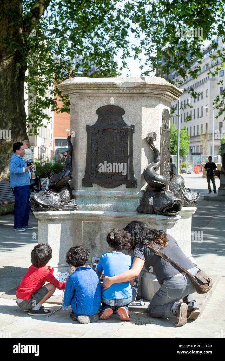 Eine Familie hockert, um die Botschaften zu lesen, die um den Sockel an der Stelle der gestürzten Statue von Edward Colston in Bristol - 8. Juni 2020 - gelegt wurden Stockfoto