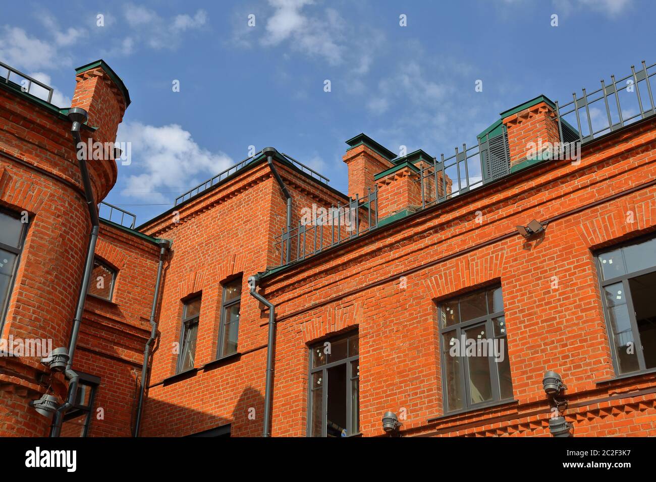 Gebäude aus hellem orangefarbenem Ziegel auf einem Hintergrund des blauen Himmels in der Tageszeit Stockfoto