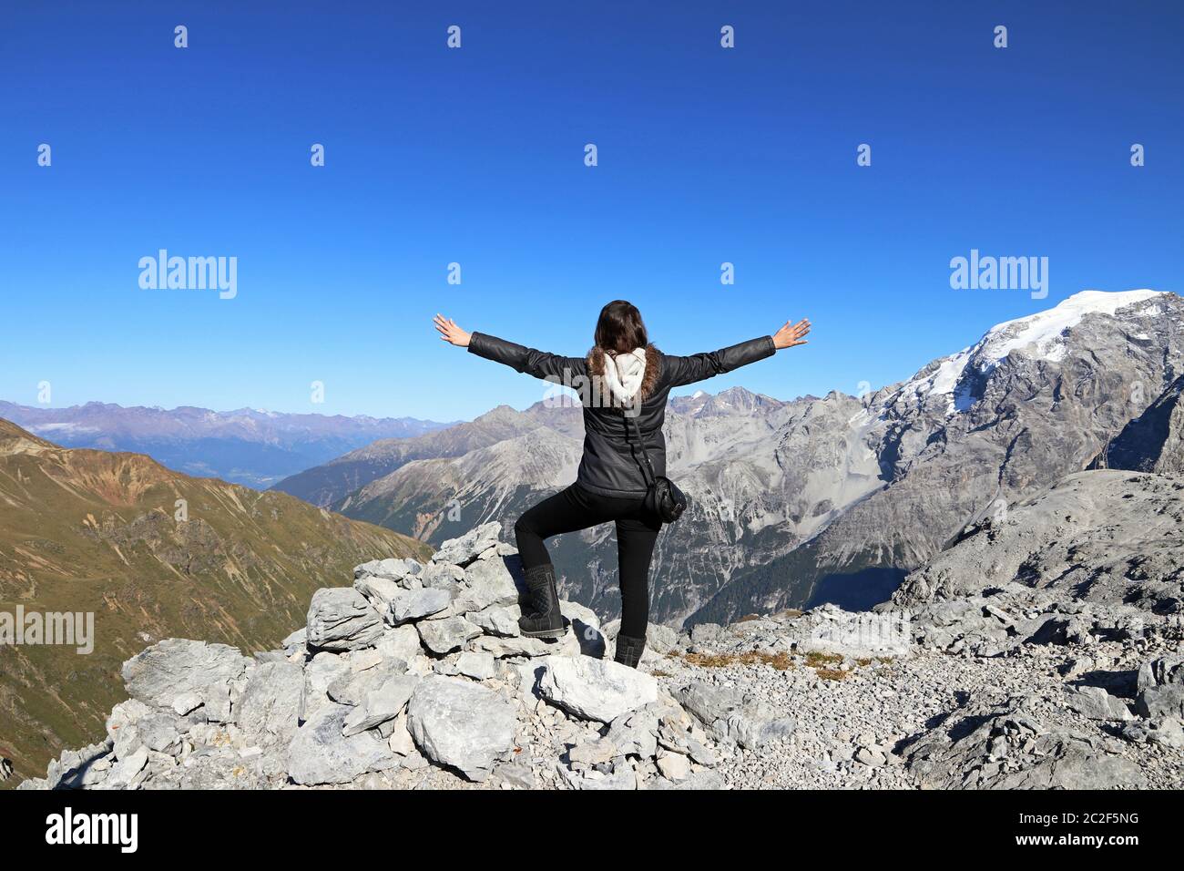 Eine Frau in den Bergen streckt ihre Arme vor Freude aus. Spaß beim Bergsteigen Stockfoto