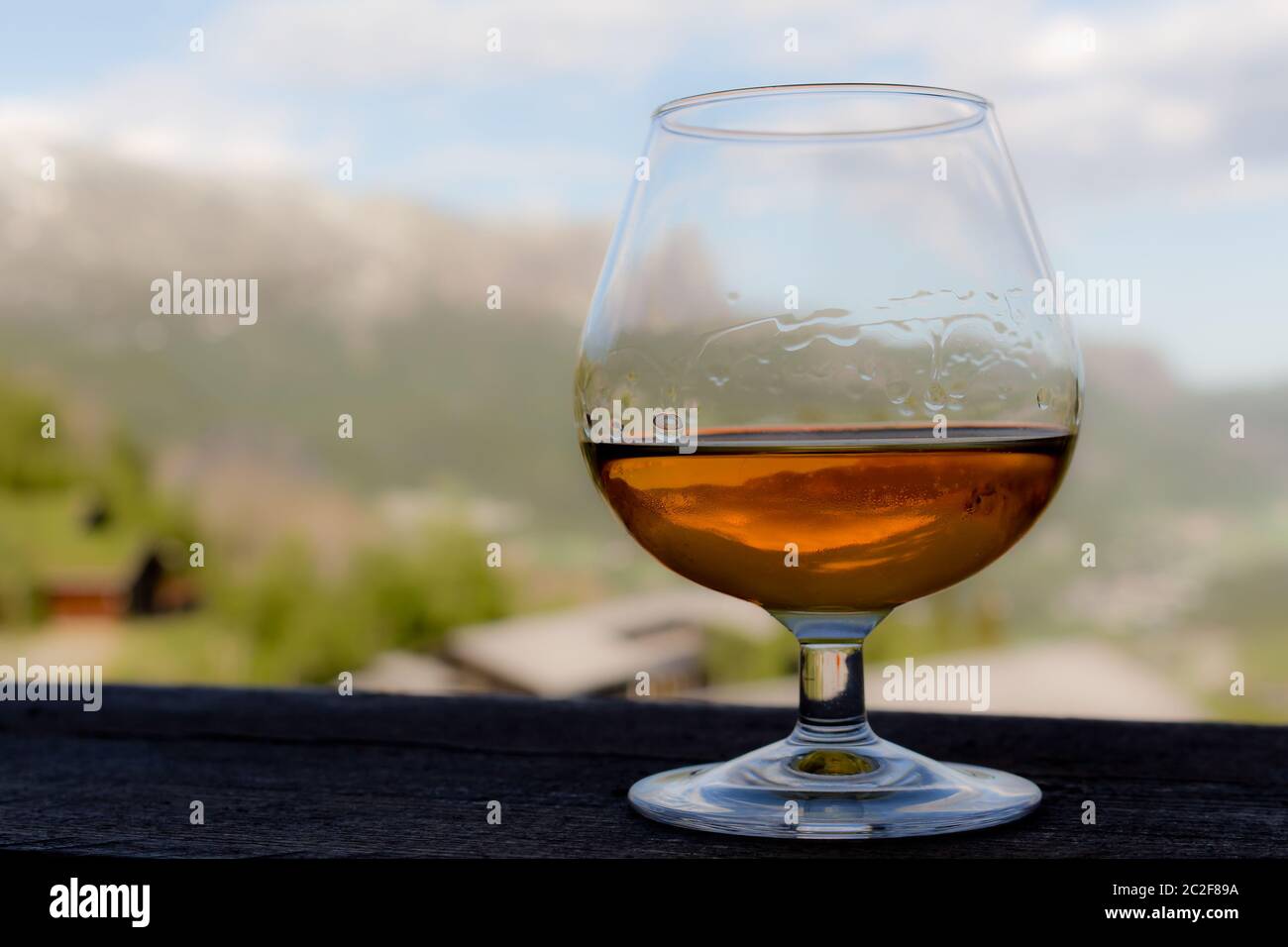 Glas mit Cognac, Whiskey oder Brandy vor idyllischer Landschaft Stockfoto