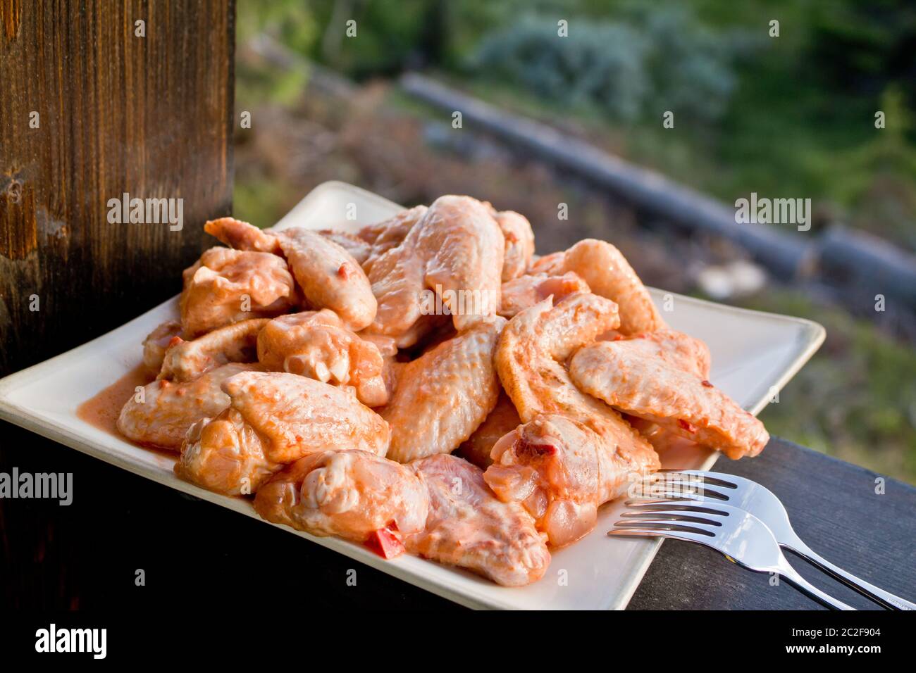 Hähnchenschenkel bereit zum Grillen auf weißem Teller Stockfoto
