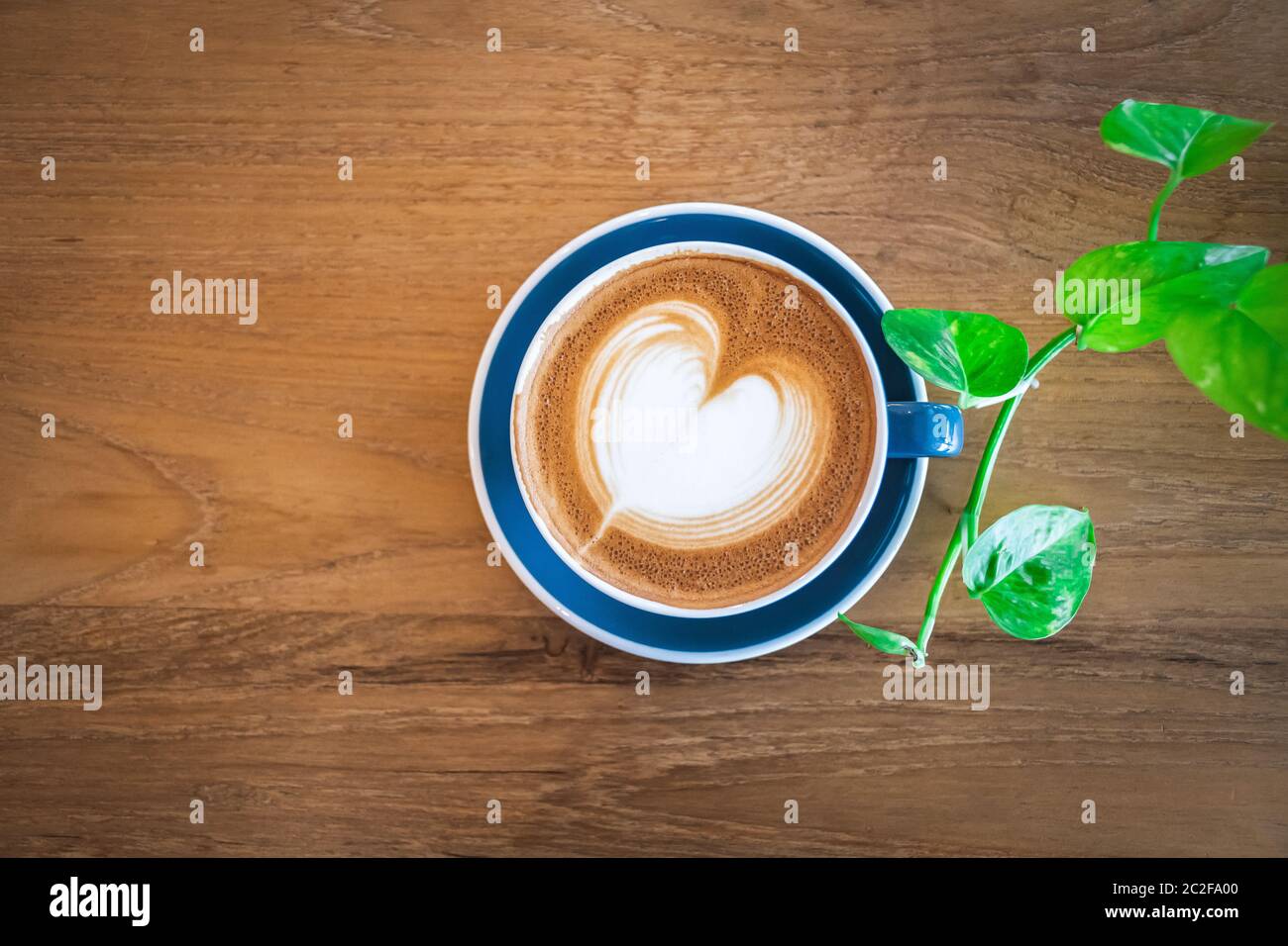 Schöne eine blaue Tasse heißen Cappuccino Kaffee mit Latte Art auf Holz Couchtisch, selektive Fokus für Getränke Hintergrund Stockfoto